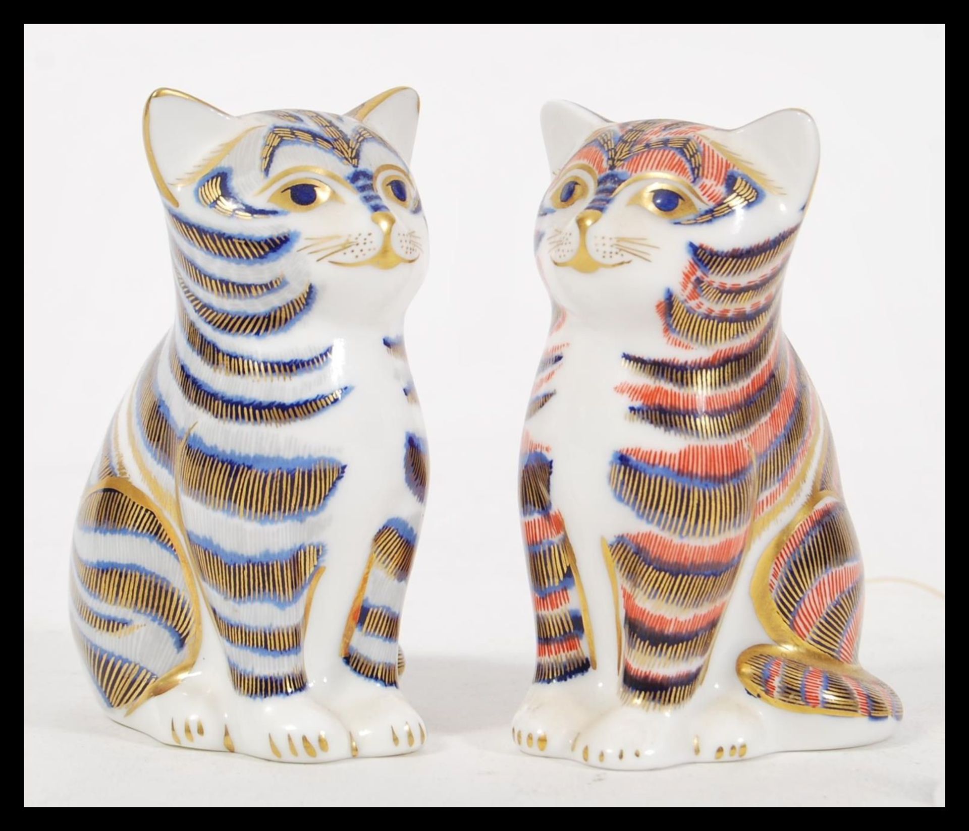 Two Crown Derby Imari ceramic paperweights in the form of cats, one having blue colouration and