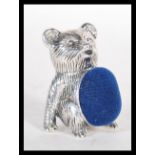 A silver pincushion in the form of a teddy bear ha