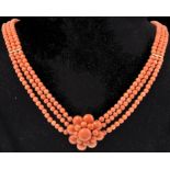 A vintage 14ct gold and coral three strand necklace. The necklace having a large coral cluster