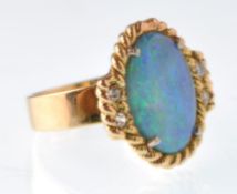 A modern black opal and diamond  gold dress ring. Centred with an oval black opal cabochon within