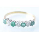 A LADIES 18CT GOLD EMERALD AND DIAMOND 7 STONE RING