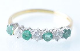 A LADIES 18CT GOLD EMERALD AND DIAMOND 7 STONE RING