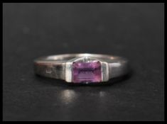 A hallmarked 9ct white gold and amethyst contemporary ring having a suspension set baguette