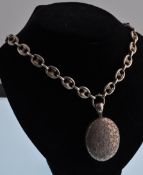A Victorian silver anchor link chain hung with an oval locket engraved with scrolls, the reverse
