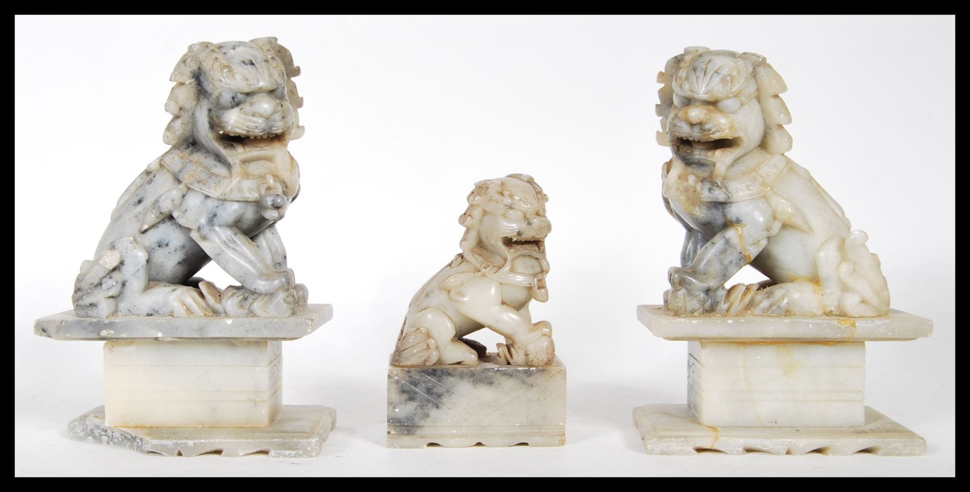 A group of three 20th Century carved fu dog soapstone figures, two matching raised on square