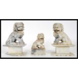 A group of three 20th Century carved fu dog soapstone figures, two matching raised on square