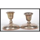 A pair of silver hallmarked filled stub candlesticks ( marks rubbed ) raised on circular terraced