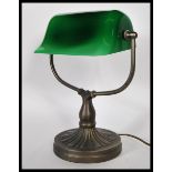 A vintage 20th century bankers desk lamp having an adjustable green glass shade raised on a brass