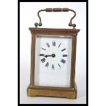 An early 20th Century French gilt brass cased carriage clock. The white enamel face with Roman