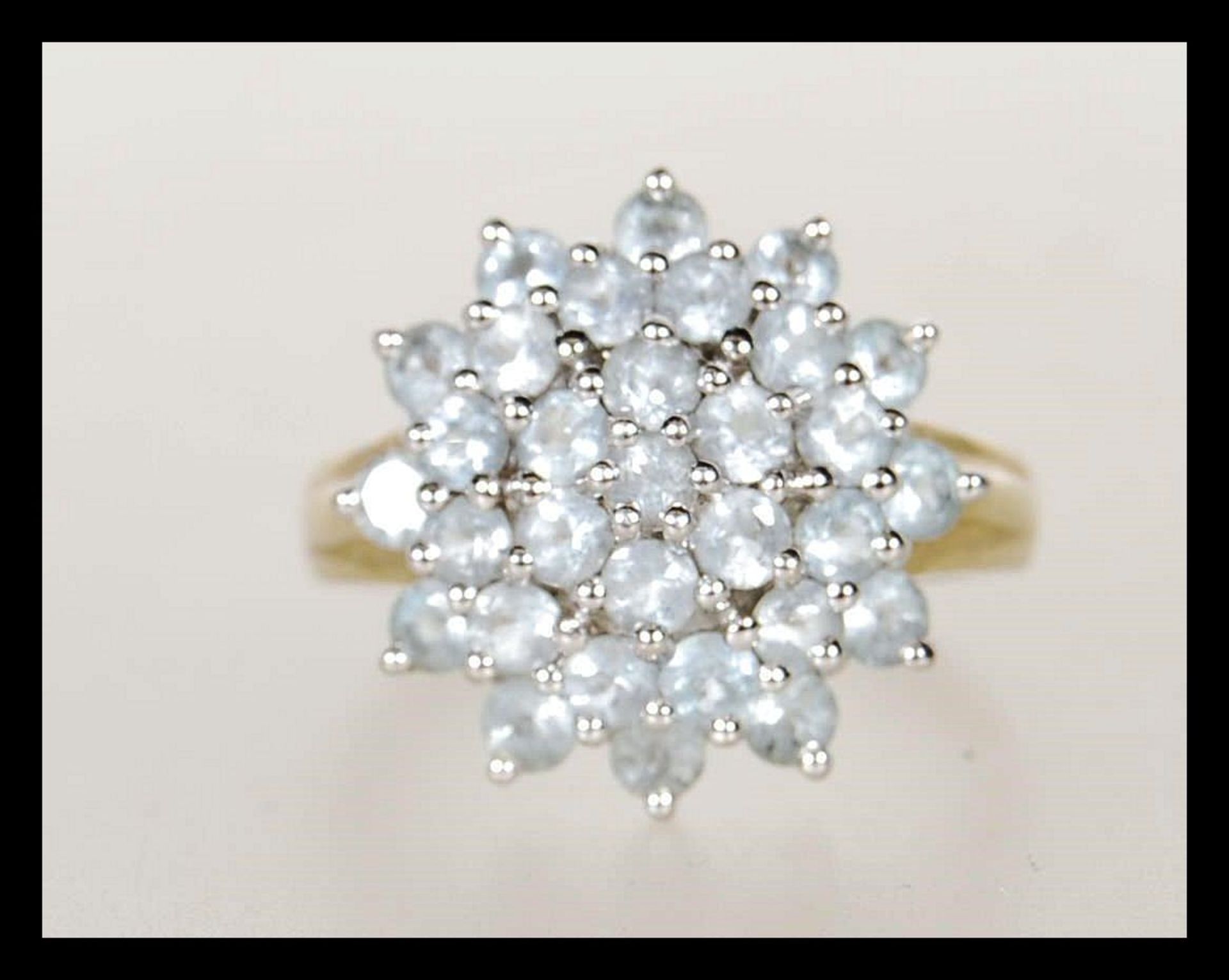 A hallmarked 9ct gold cluster ring being set with a round cluster of white stones. Hallmarked