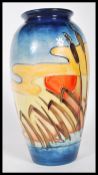 A Moorcroft Pottery tube lined ' Reeds of sunset ' pattern vase depicting a sunset over a waters