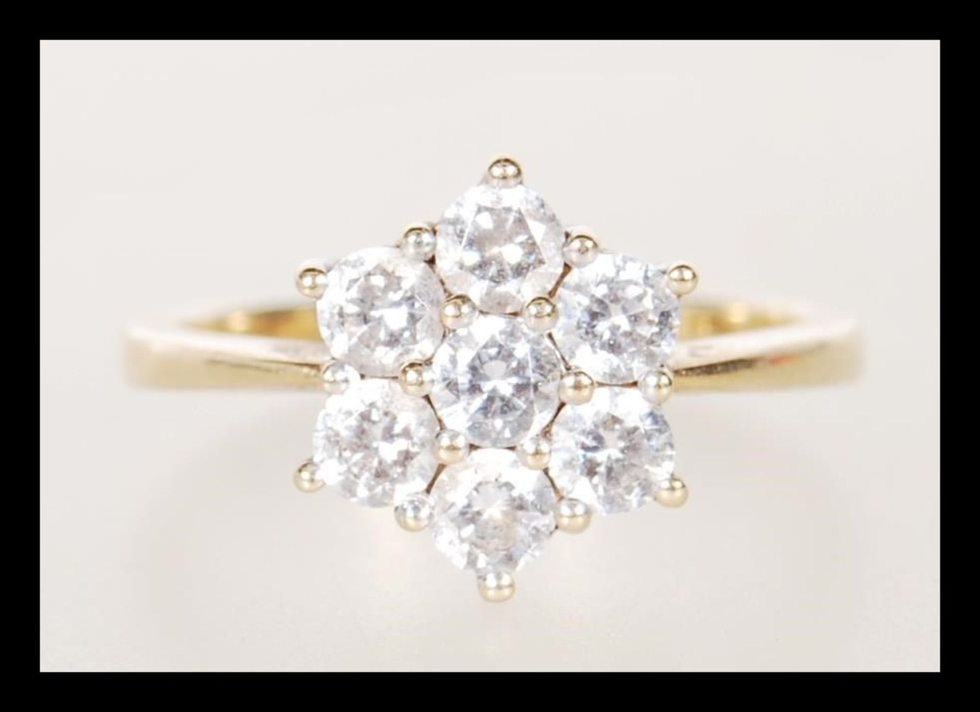 A 14ct gold ladies dress ring having a flower head prong set with seven white stones. Stamped with