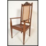 A Victorian Arts & Crafts oak carver cane back armchair. Raised on square tapering legs with