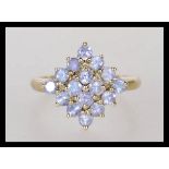 A hallmarked 9ct gold ladies cluster ring prong set with lilac stones in a geometric formation.