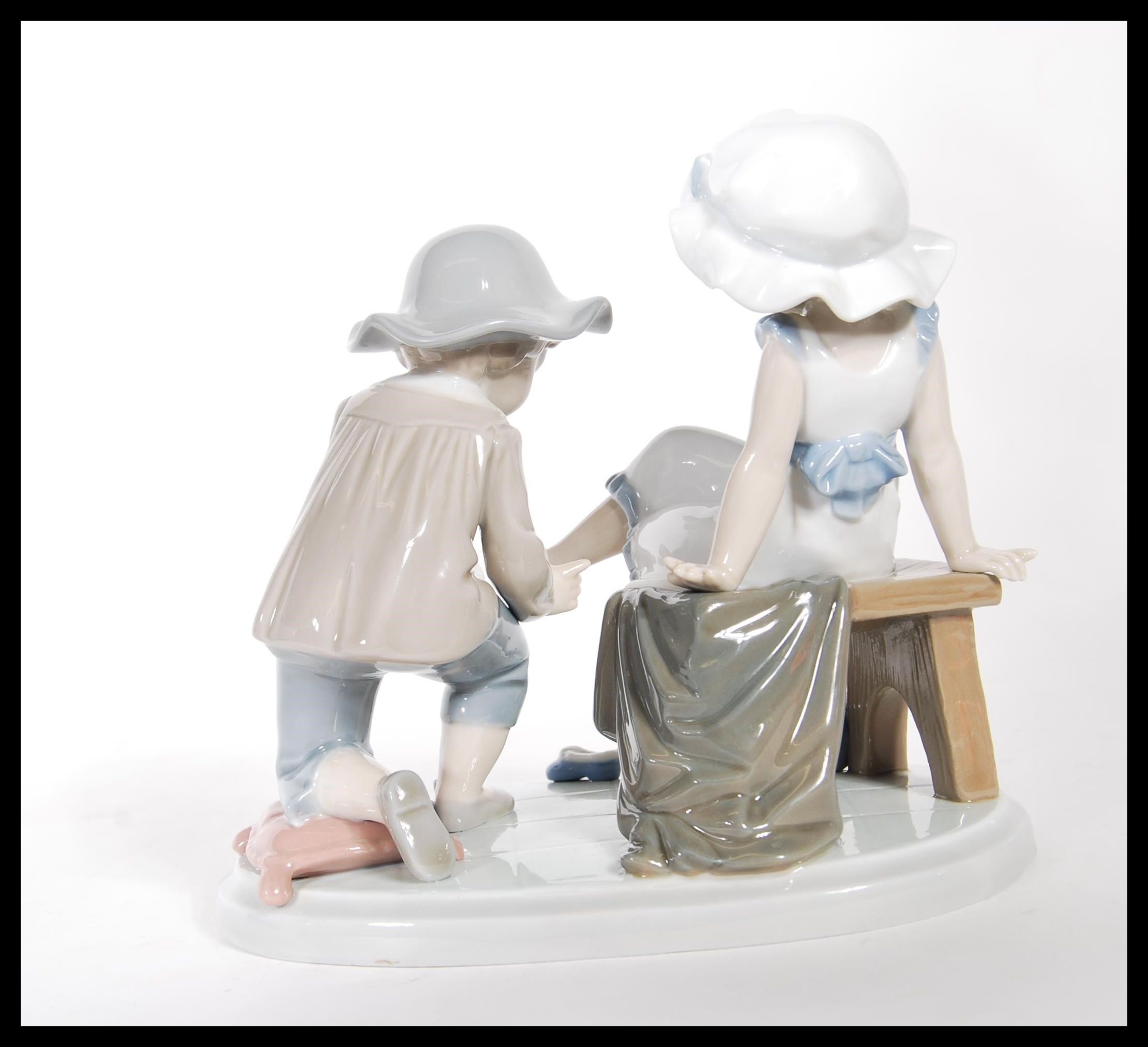 A Lladro ceramic figure group titled ' Try this One ', (5361) of a young girl trying on a shoe. - Image 3 of 6