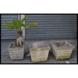 A group of three reconstituted stone garden troughs / planters, each of square form and moulded to