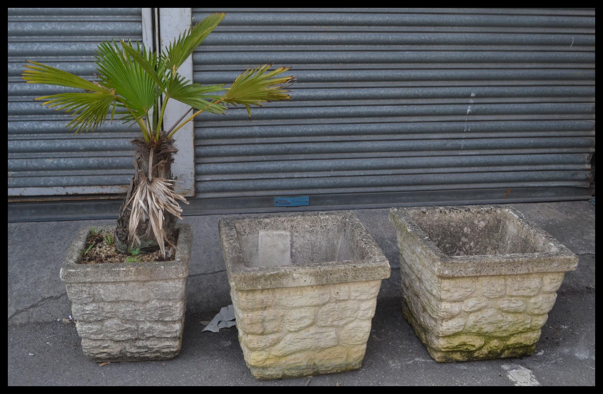 A group of three reconstituted stone garden troughs / planters, each of square form and moulded to