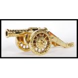 A 20th Century gilt brass desktop cannon ornament having twin wheels with raised garland