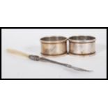 A pair of silver hallmarked napkin rings along with a silver plate toasting fork having scrolled