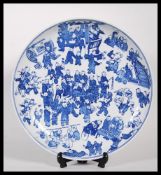 A large Chinese blue and white charger plate depicting 100 children. Concentric circles and