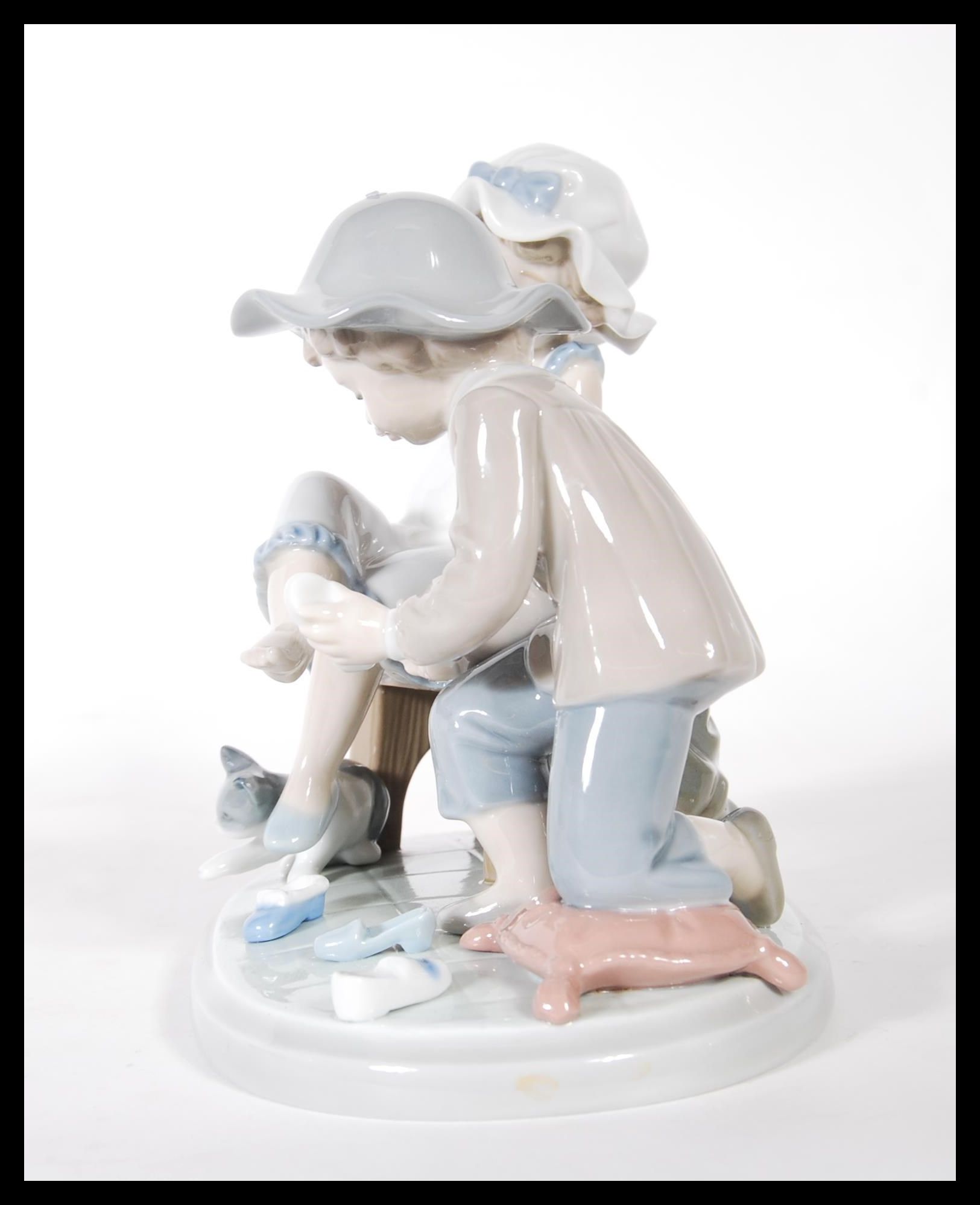 A Lladro ceramic figure group titled ' Try this One ', (5361) of a young girl trying on a shoe. - Image 4 of 6