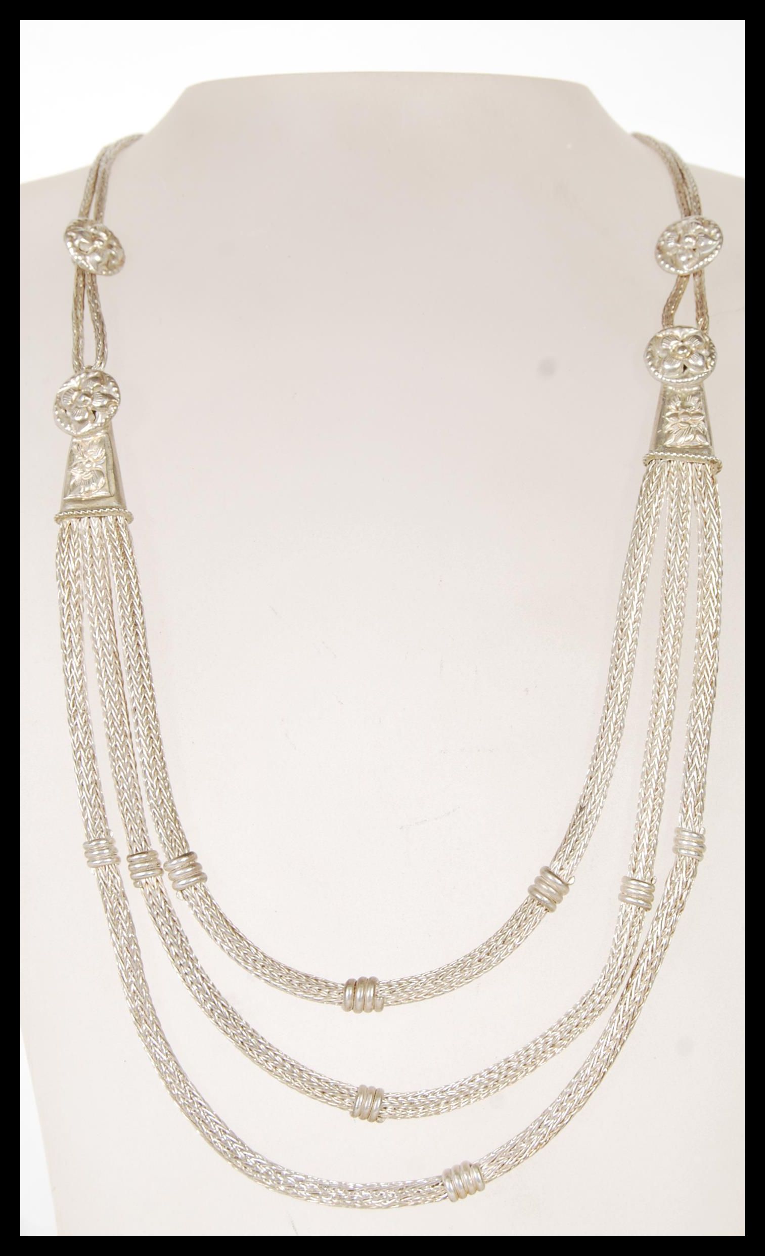A 20th Century ethnic style silver necklace having three graduating snake chains with engraved