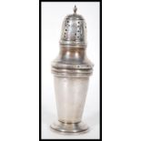 A silver hallmarked sugar shaker of tapering cylindrical form being raised on a stepped round base