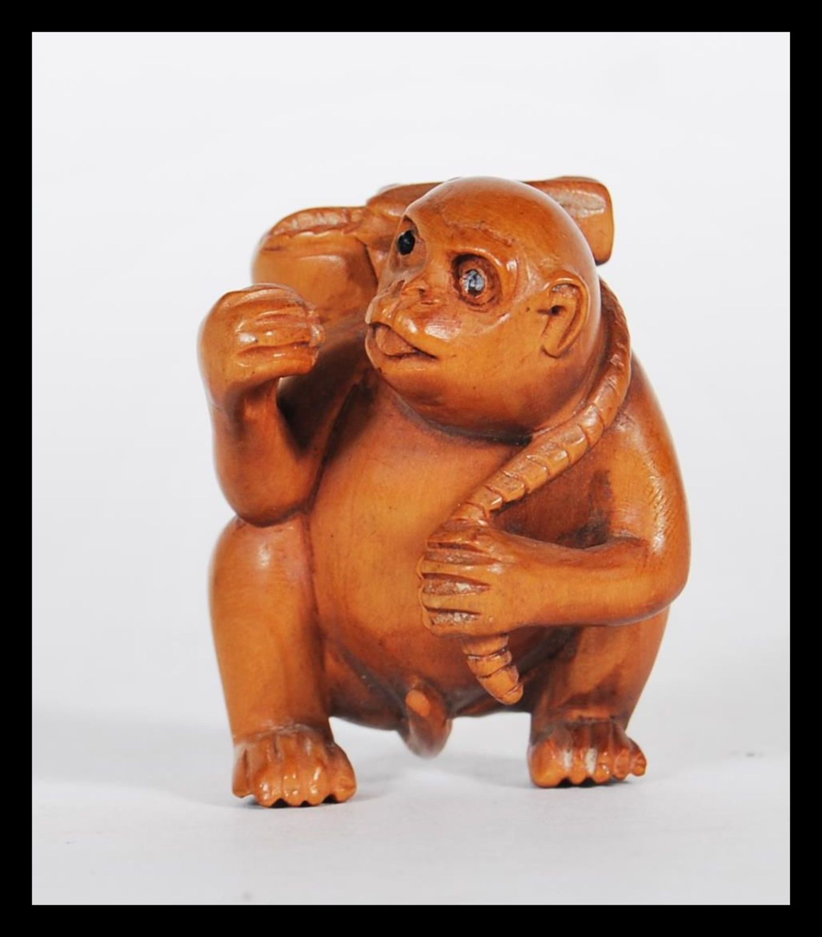 A 20th Century Japanese carved wood netsuke in the form of a monkey carrying a fruit to its back.