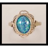 A hallmarked 9ct gold ladies dress ring set with a blue opalescent cabochon in a decorative setting.