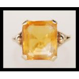 A 9ct gold dress ring, prong set with a square cut orange stone on a split shank mount. Unmarked but