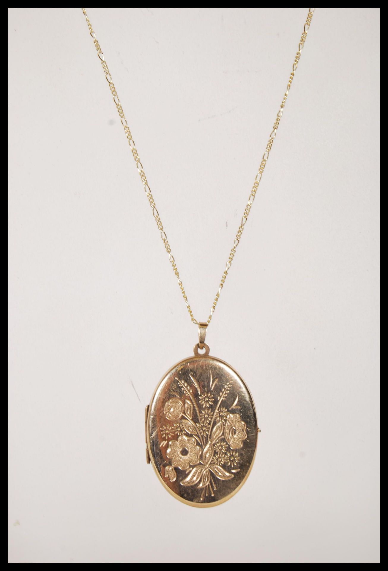 A stamped 375 9 ct gold necklace having a fine Figaro chain (stamped 375) with a locket pendant