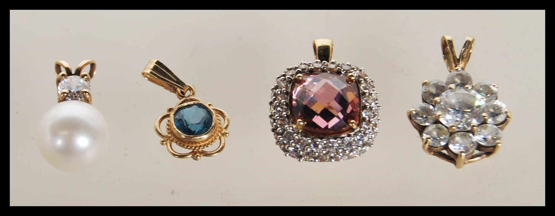 A selection of 9ct gold pendants to include a square pendant set with a faceted pink stone and white