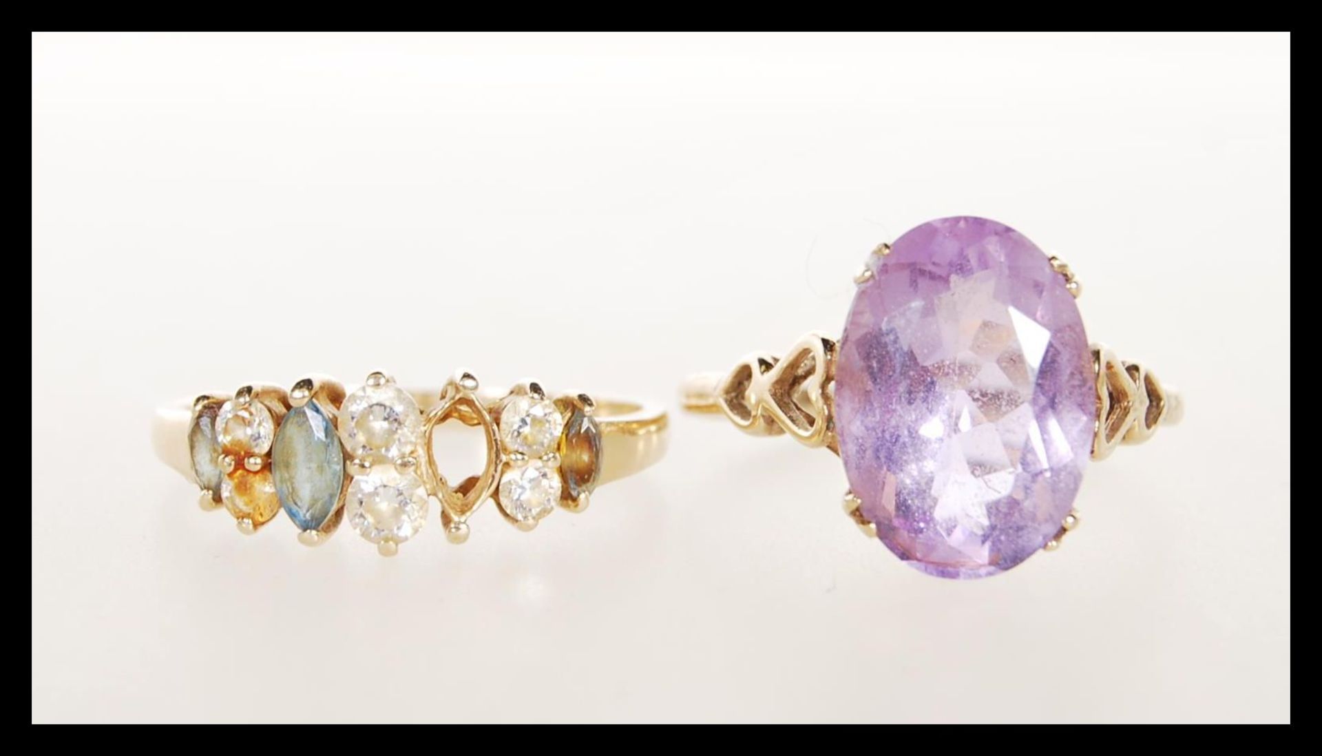 A stamped 375 9ct gold ladies dress ring being set with a an oval cut purple stone having pierced