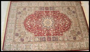 A large Persian floor carpet Keshan rug having a red ground with geometric borders and medallions.