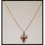 A 9ct gold openwork heart shaped pendant necklace, having a red stone to centre, with floral design,