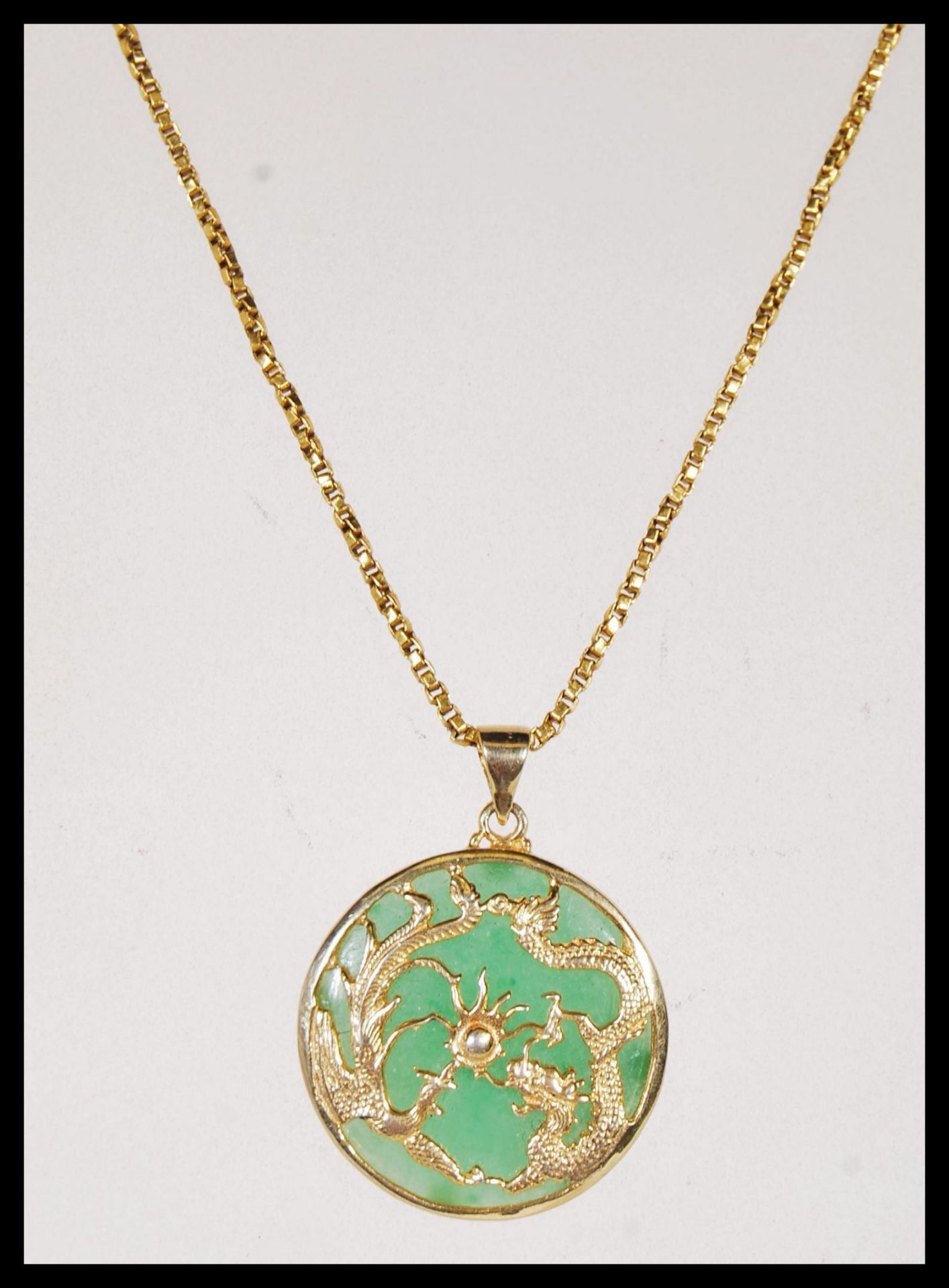 A gold on silver stamped 925 Chinese Jade pendant of circular form, having Dragon and Phoenix
