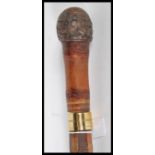 A 20th Century walking sword stick having carved rounded knob and brass band. Handle pulls off to