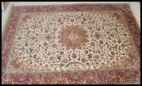 A large Persian floor carpet Keshan rug having a beige ground with geometric borders and medallions.