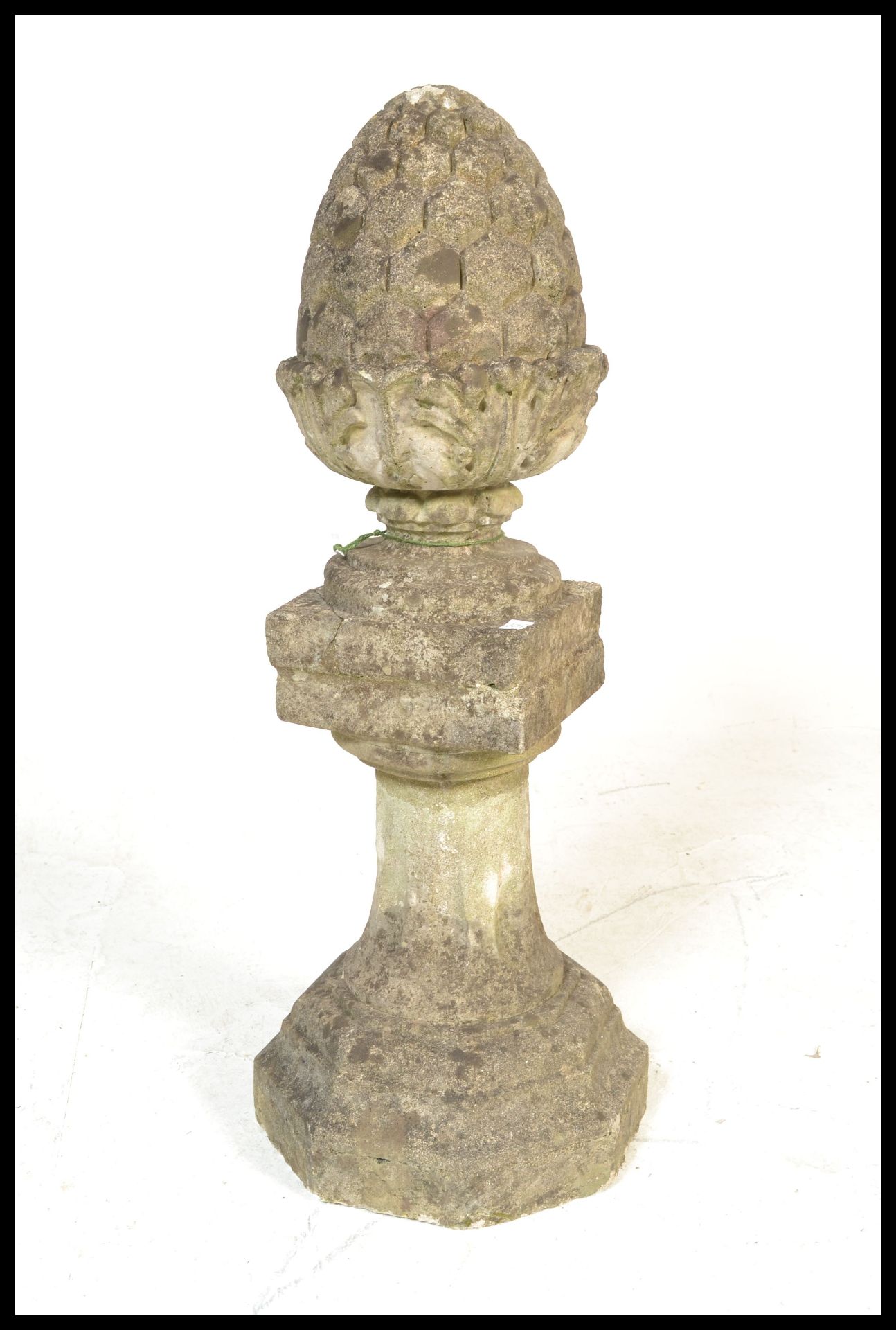 A well weathered reconstituted garden / gate stone acorn finial raised on a baluster pedestal