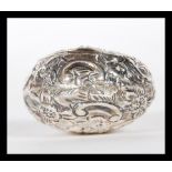 An early 20th Century silver hallmarked snuff / pill box of bulbous form having repousse floral