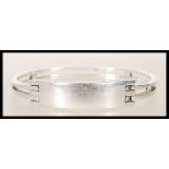 A stamped 925 silver bangle bracelet having square bars culminating in a square geometric clasp.
