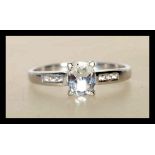 A hallmarked 9ct white gold ladies ring prong set with a oval cut white stone having accent stones