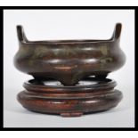 A Chinese bronze censer ding prayer bowl raised on three conical feet and twin hoop handles.