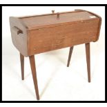 A vintage retro wooden sewing box having twin doors with knob handles to the top, raised on tapering