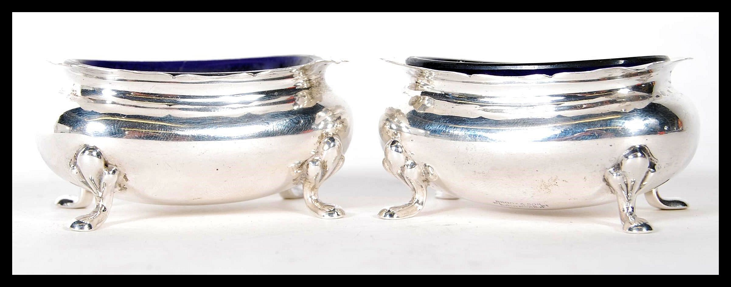 A pair of silver hallmarked Brook & Sons of Edinburgh blue glass lined table salts, all raised on