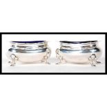 A pair of silver hallmarked Brook & Sons of Edinburgh blue glass lined table salts, all raised on