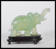 A 20th Century Chinese carved jadeite elephant on all four legs raised on a ebonised wooden base.