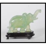 A 20th Century Chinese carved jadeite elephant on all four legs raised on a ebonised wooden base.