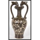 A Chinese stoneware vase / urn having shaped twin handles with floral relief decoration to the