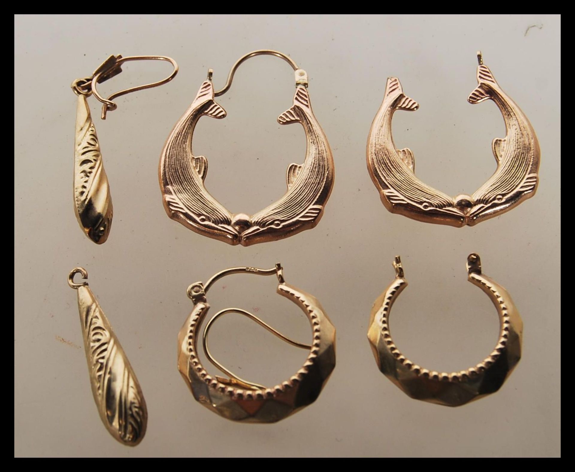 A group of three pairs of 9ct gold earrings to include a pair of dolphin design hoop earrings, a